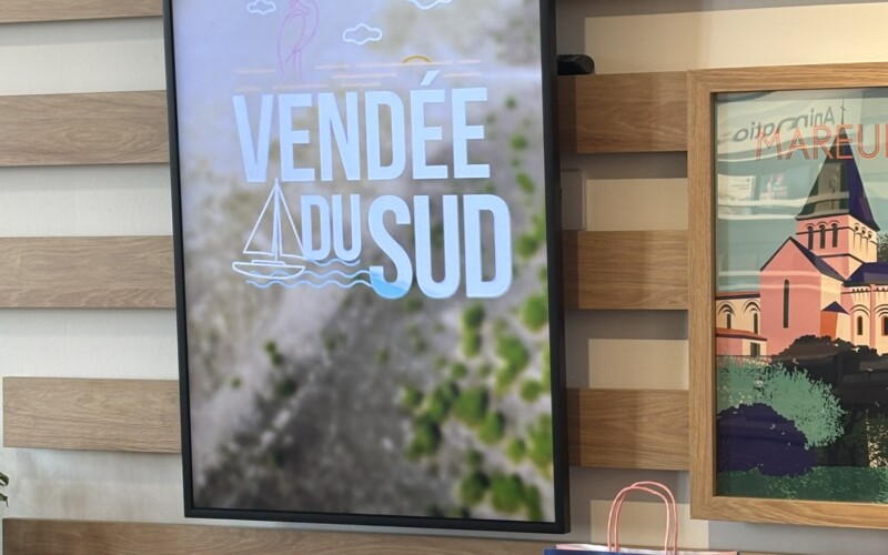 Affichage dynamique dans l'Office de Tourisme intégré au site : écran Samsung en mode portrait, encastré dans la cloison bois, diffusant les contenus de la marque Vendée du Sud. Écran Samsung en mode portrait dans l'Office de Tourisme de La Distylerie, affichage dynamique Vendée du Sud